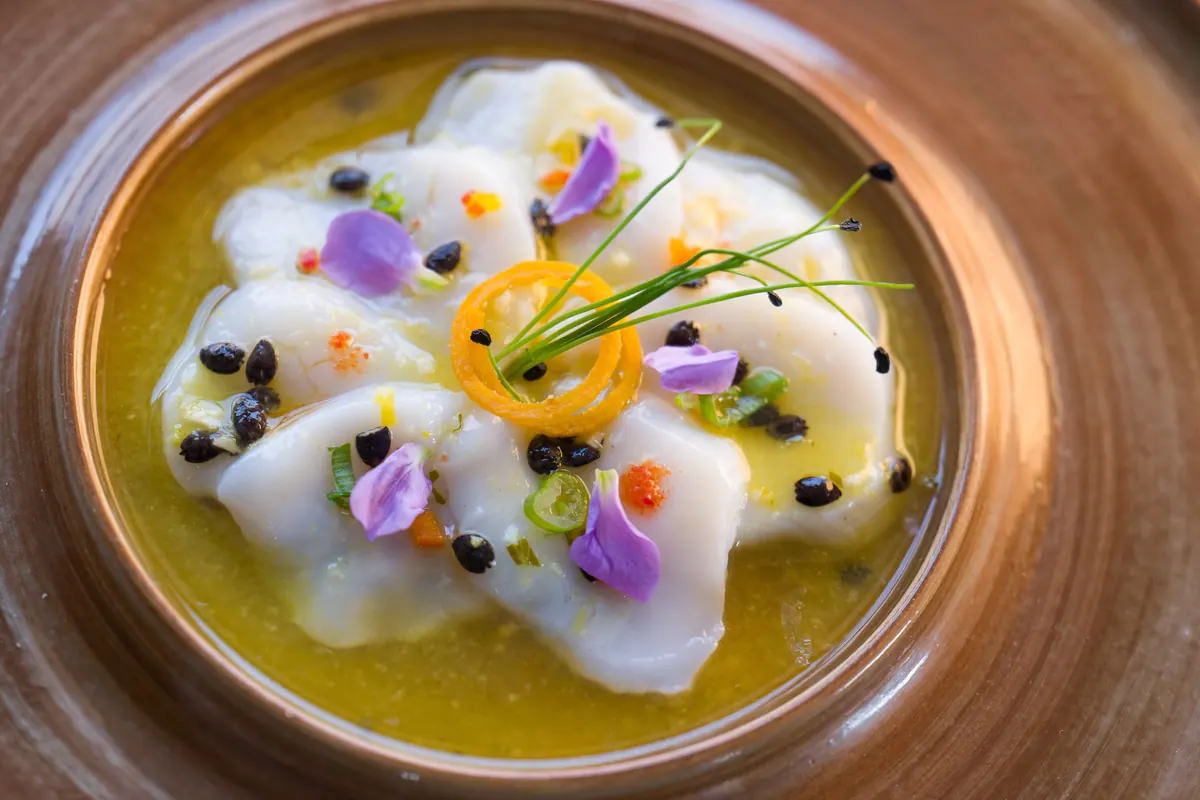 Apasionada: sliced scallops in passion fruit leche de tigre with edible flowers
